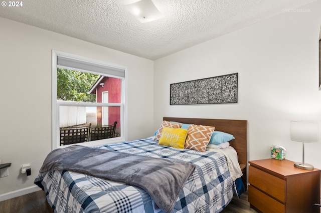 bedroom with a textured ceiling and dark hardwood / wood-style floors