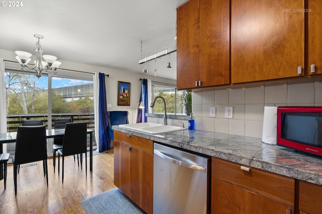 kitchen with decorative backsplash, stainless steel dishwasher, light hardwood / wood-style flooring, a notable chandelier, and sink