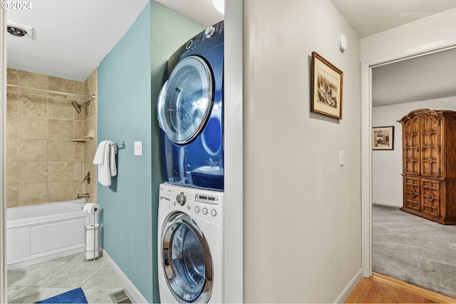 laundry area featuring stacked washer / drying machine and light carpet