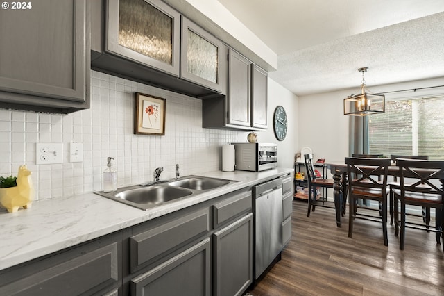 kitchen with a sink, an inviting chandelier, backsplash, gray cabinetry, and appliances with stainless steel finishes