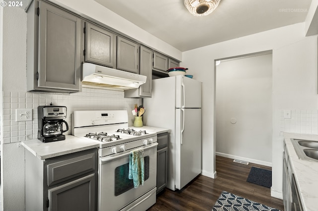 kitchen with under cabinet range hood, white appliances, backsplash, and gray cabinets