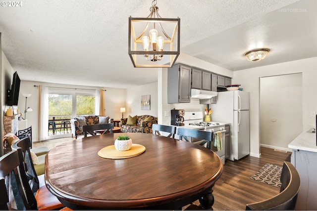 dining area featuring dark wood-type flooring, a textured ceiling, baseboards, and an inviting chandelier