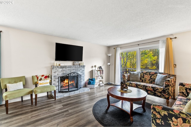 living area with a brick fireplace, wood finished floors, a textured ceiling, and baseboards