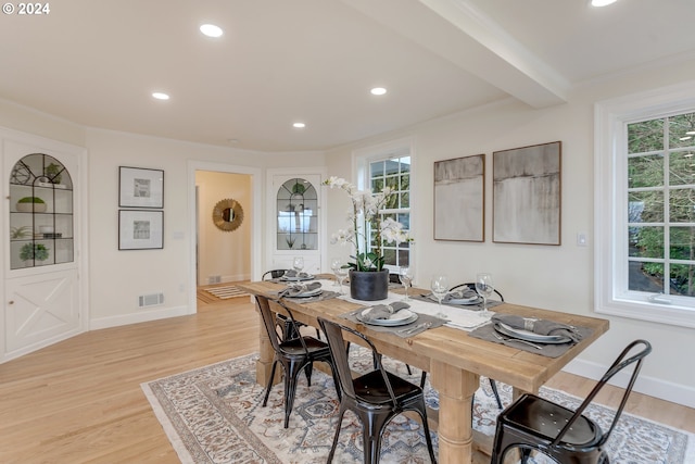 dining space featuring beam ceiling, light hardwood / wood-style flooring, and crown molding