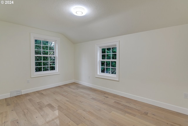 bonus room featuring a textured ceiling, light hardwood / wood-style flooring, and lofted ceiling