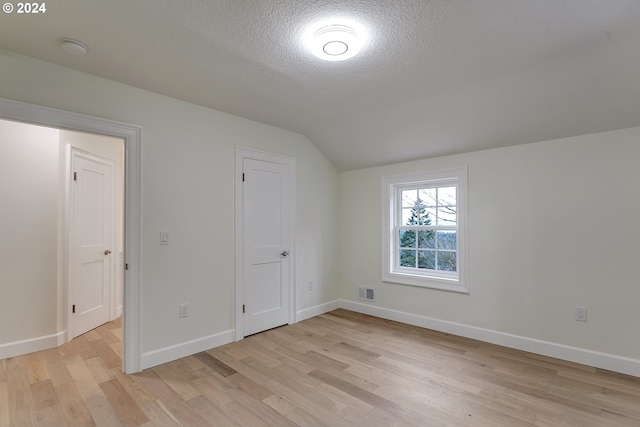 bonus room with light wood-type flooring, a textured ceiling, and lofted ceiling