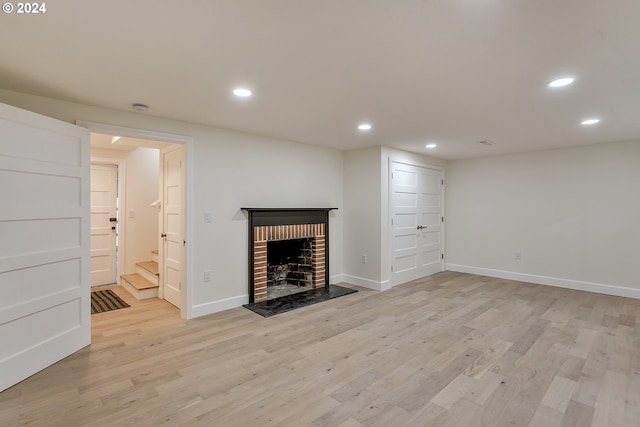 unfurnished living room featuring light hardwood / wood-style floors and a brick fireplace