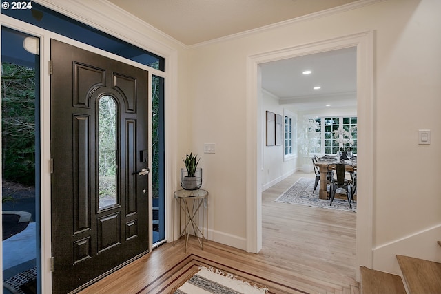 entrance foyer featuring a healthy amount of sunlight, light wood-type flooring, and crown molding