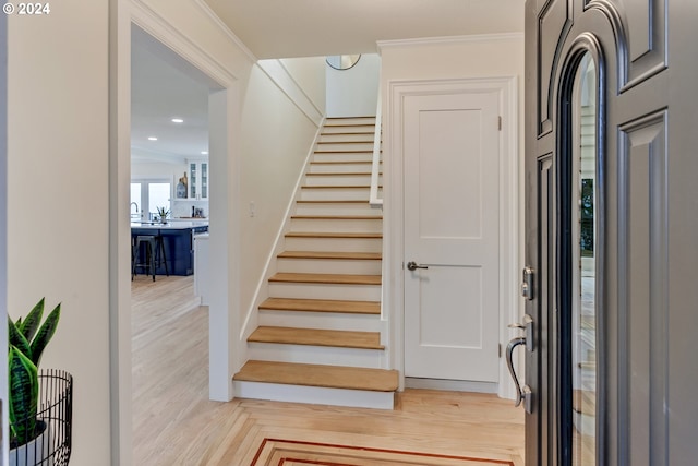 entryway with wood-type flooring and ornamental molding