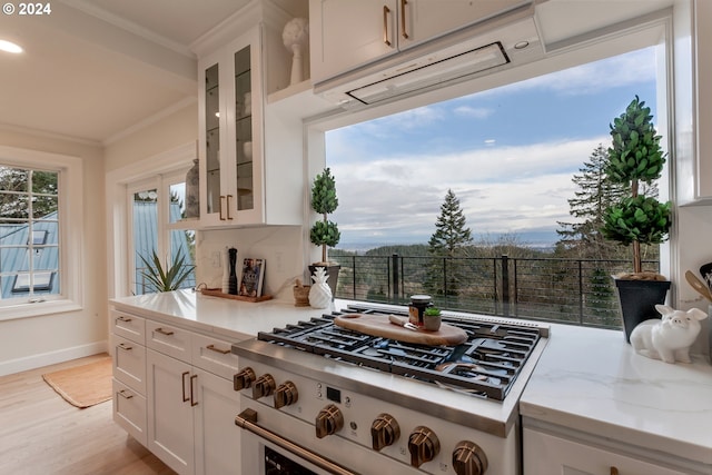 kitchen featuring range, ornamental molding, light wood-type flooring, light stone counters, and white cabinetry