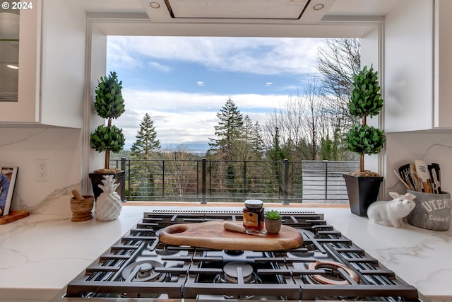 kitchen featuring white cabinets, stainless steel gas stovetop, and light stone counters