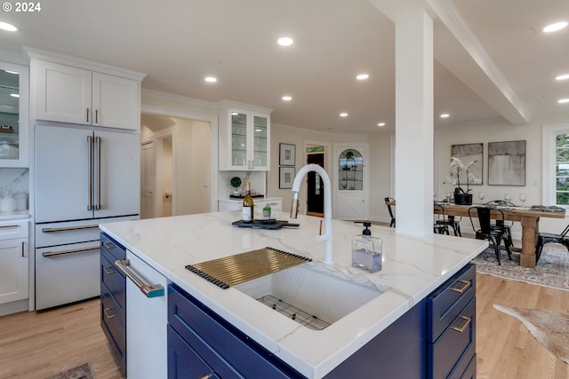 kitchen with high end white refrigerator, a center island, white cabinetry, and sink