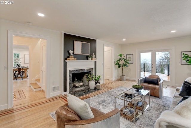 living room featuring a fireplace, french doors, light wood-type flooring, and crown molding