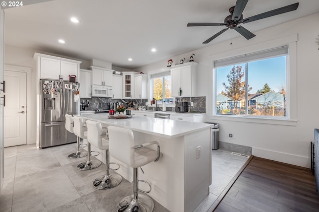 kitchen with white cabinets, appliances with stainless steel finishes, a center island, and a kitchen bar