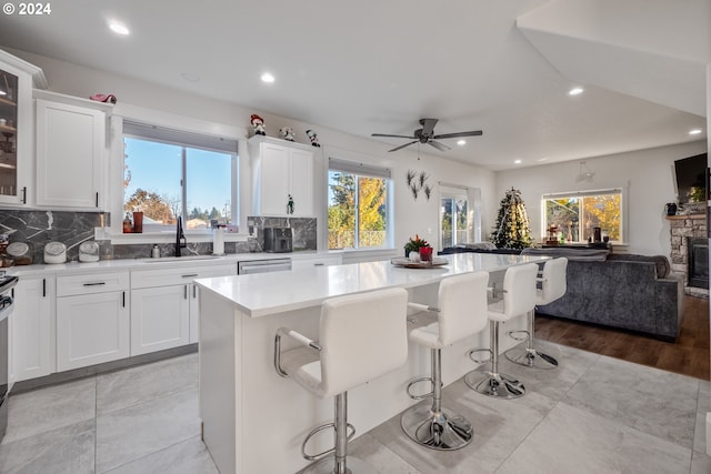 kitchen with a kitchen breakfast bar, a center island, white cabinetry, and sink