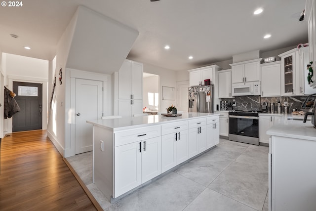 kitchen featuring appliances with stainless steel finishes, sink, a center island, light hardwood / wood-style floors, and white cabinetry