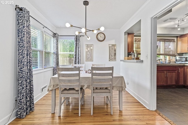 dining area with a chandelier, light wood-type flooring, and ornamental molding