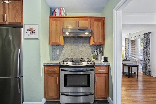 kitchen featuring decorative backsplash, crown molding, wood-type flooring, and appliances with stainless steel finishes