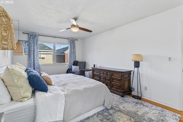 bedroom with ceiling fan, light hardwood / wood-style floors, and a textured ceiling