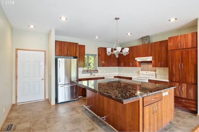 kitchen with pendant lighting, white appliances, sink, a kitchen island, and a chandelier