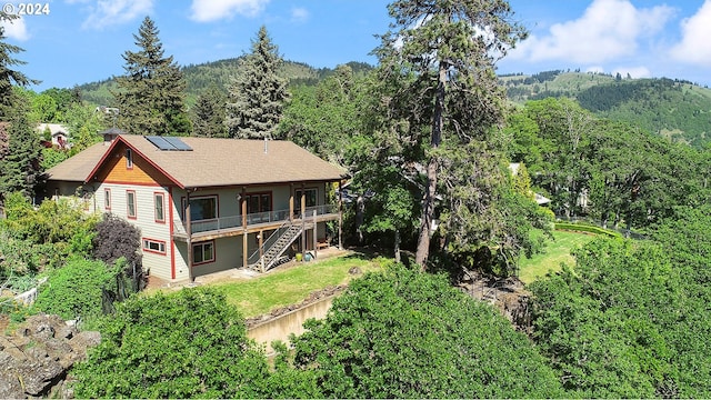 rear view of property with a deck with mountain view and solar panels