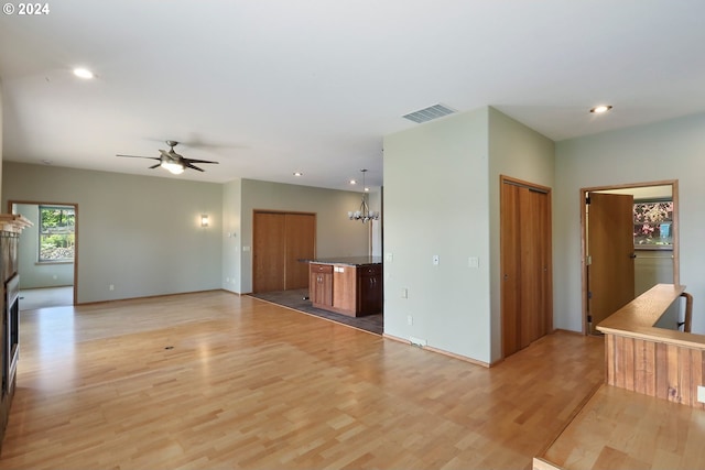 unfurnished living room featuring light hardwood / wood-style flooring and ceiling fan with notable chandelier