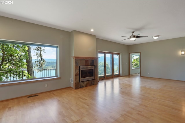 unfurnished living room featuring light hardwood / wood-style floors, a wealth of natural light, and a tiled fireplace