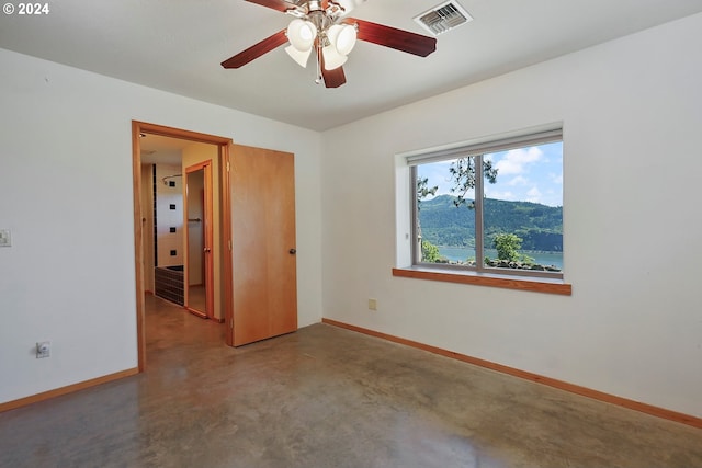 empty room featuring a mountain view, ceiling fan, and concrete flooring