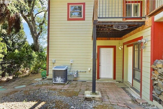 view of exterior entry featuring cooling unit and a patio area