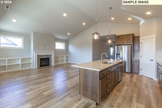 kitchen featuring appliances with stainless steel finishes, an island with sink, vaulted ceiling, and sink