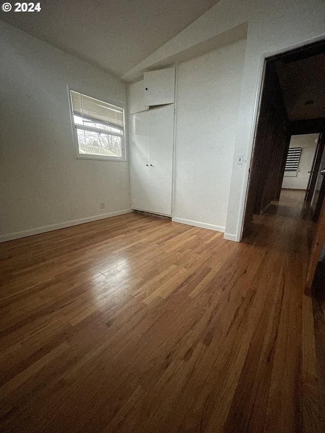 unfurnished bedroom with hardwood / wood-style flooring, a closet, and lofted ceiling