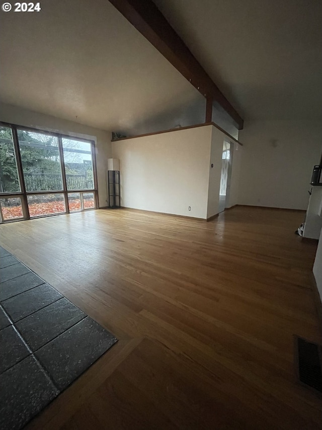 unfurnished living room featuring vaulted ceiling with beams and hardwood / wood-style flooring