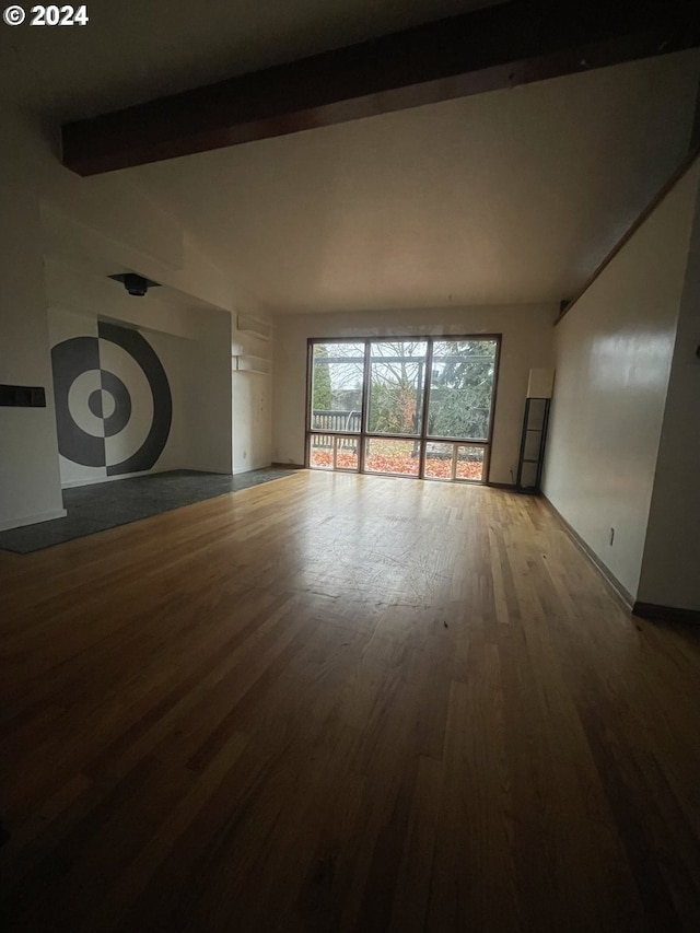 unfurnished living room featuring hardwood / wood-style floors and beam ceiling