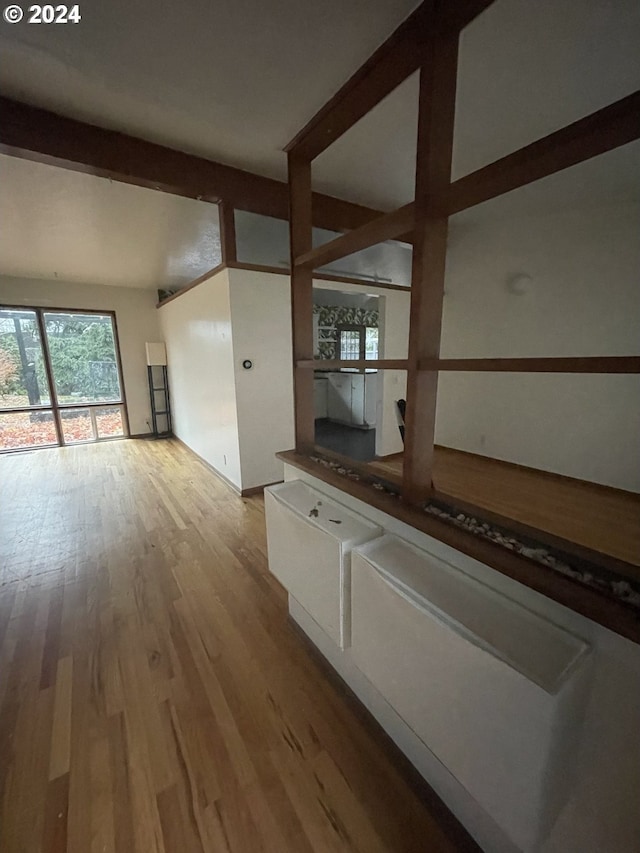 corridor with beamed ceiling and light hardwood / wood-style floors