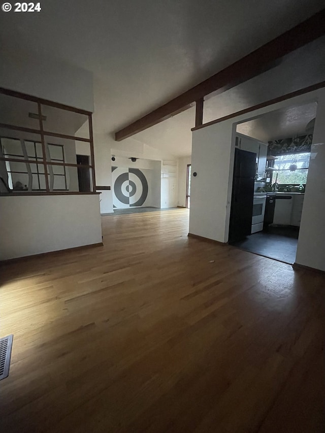 unfurnished living room featuring beamed ceiling and wood-type flooring