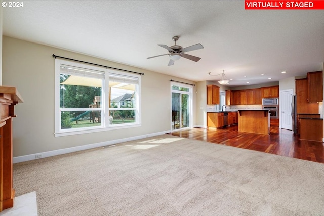 unfurnished living room with ceiling fan, dark hardwood / wood-style floors, and sink