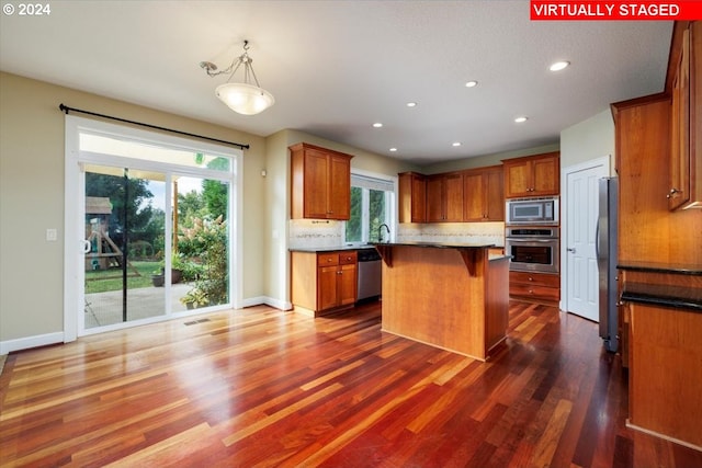 kitchen with a center island, stainless steel appliances, dark hardwood / wood-style floors, and hanging light fixtures