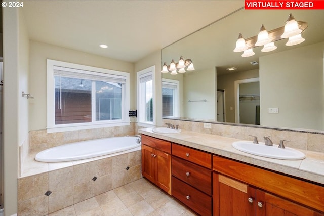 bathroom featuring tile patterned flooring, tiled bath, and vanity