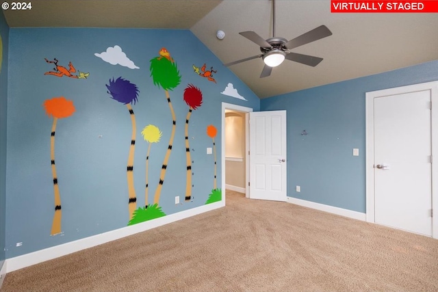 interior space with lofted ceiling, ceiling fan, and carpet floors