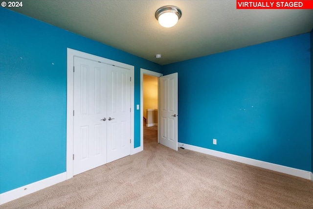 unfurnished bedroom featuring a textured ceiling, carpet, and a closet