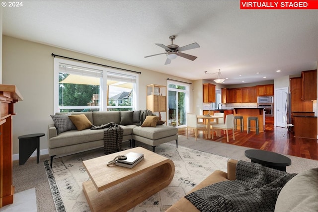 living room featuring plenty of natural light, ceiling fan, and wood-type flooring