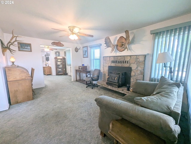 carpeted living room featuring a wood stove, a fireplace, and ceiling fan