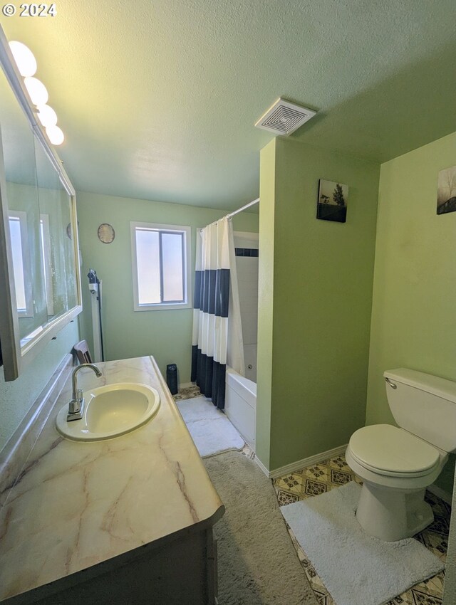 full bathroom with shower / tub combo with curtain, vanity, a textured ceiling, and toilet