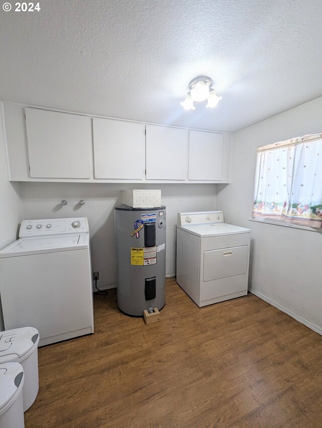 washroom with electric water heater, hardwood / wood-style flooring, cabinets, and washing machine and clothes dryer