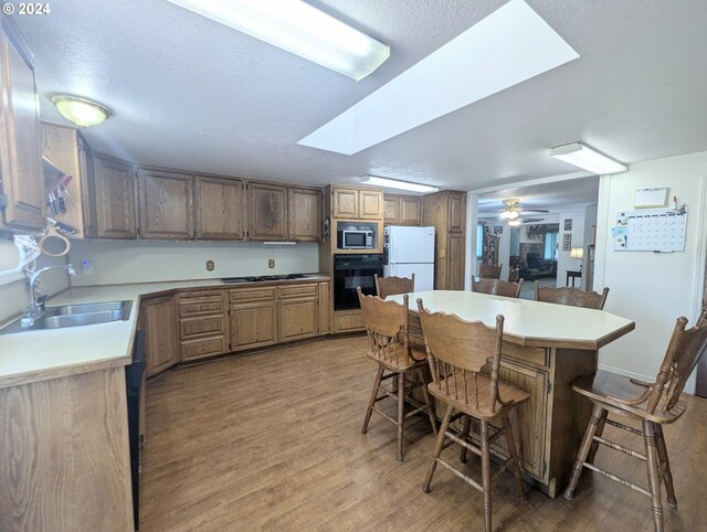 kitchen featuring ceiling fan, stainless steel appliances, sink, dark hardwood / wood-style floors, and a kitchen breakfast bar