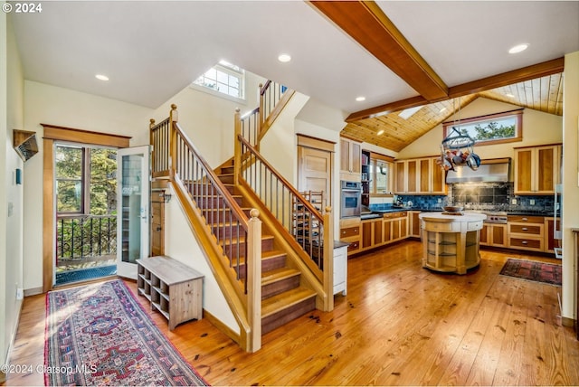 kitchen with stainless steel oven, a healthy amount of sunlight, light wood-type flooring, and a kitchen island