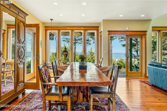 dining space with light hardwood / wood-style flooring and a water view