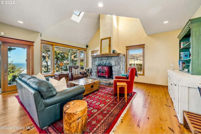 living room featuring a wealth of natural light, high vaulted ceiling, a skylight, and light hardwood / wood-style floors