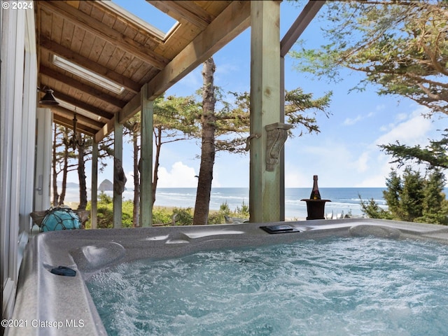 view of pool with a hot tub and a water view