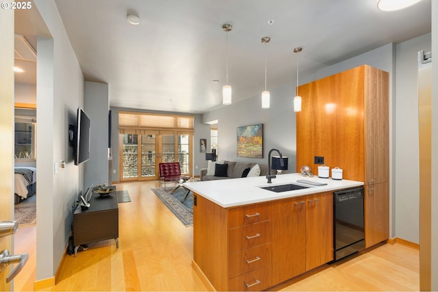 kitchen featuring a peninsula, a sink, open floor plan, light countertops, and dishwasher